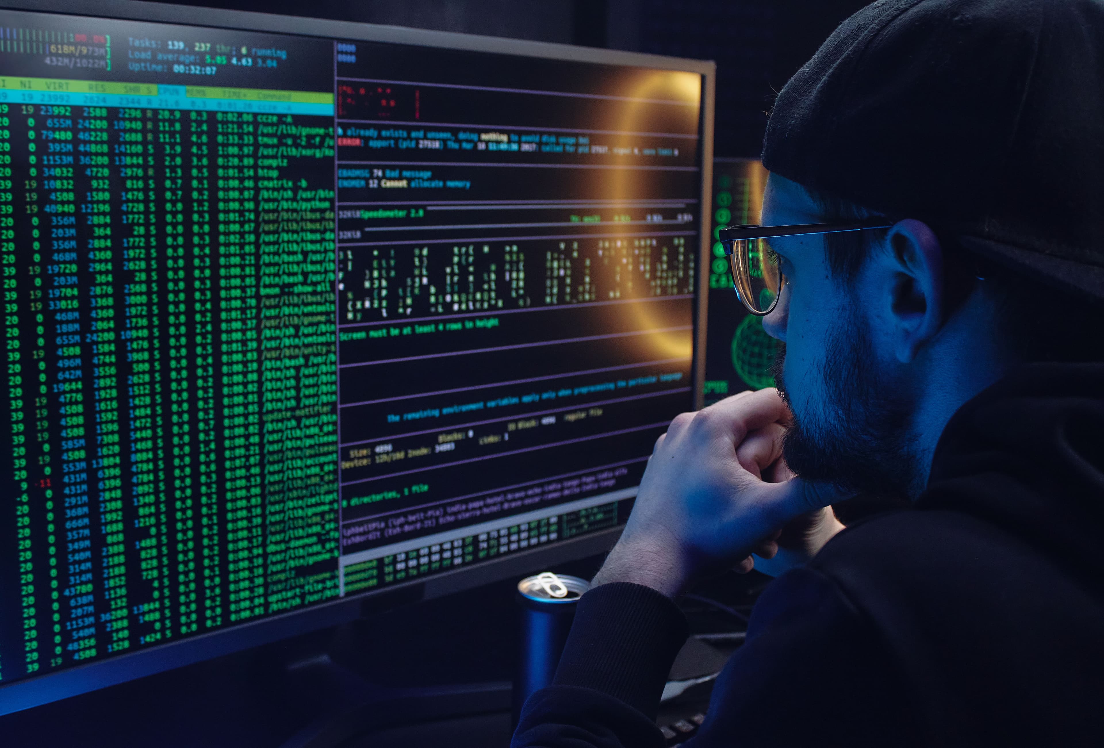 Person reviewing terminal output and system data on multiple monitors