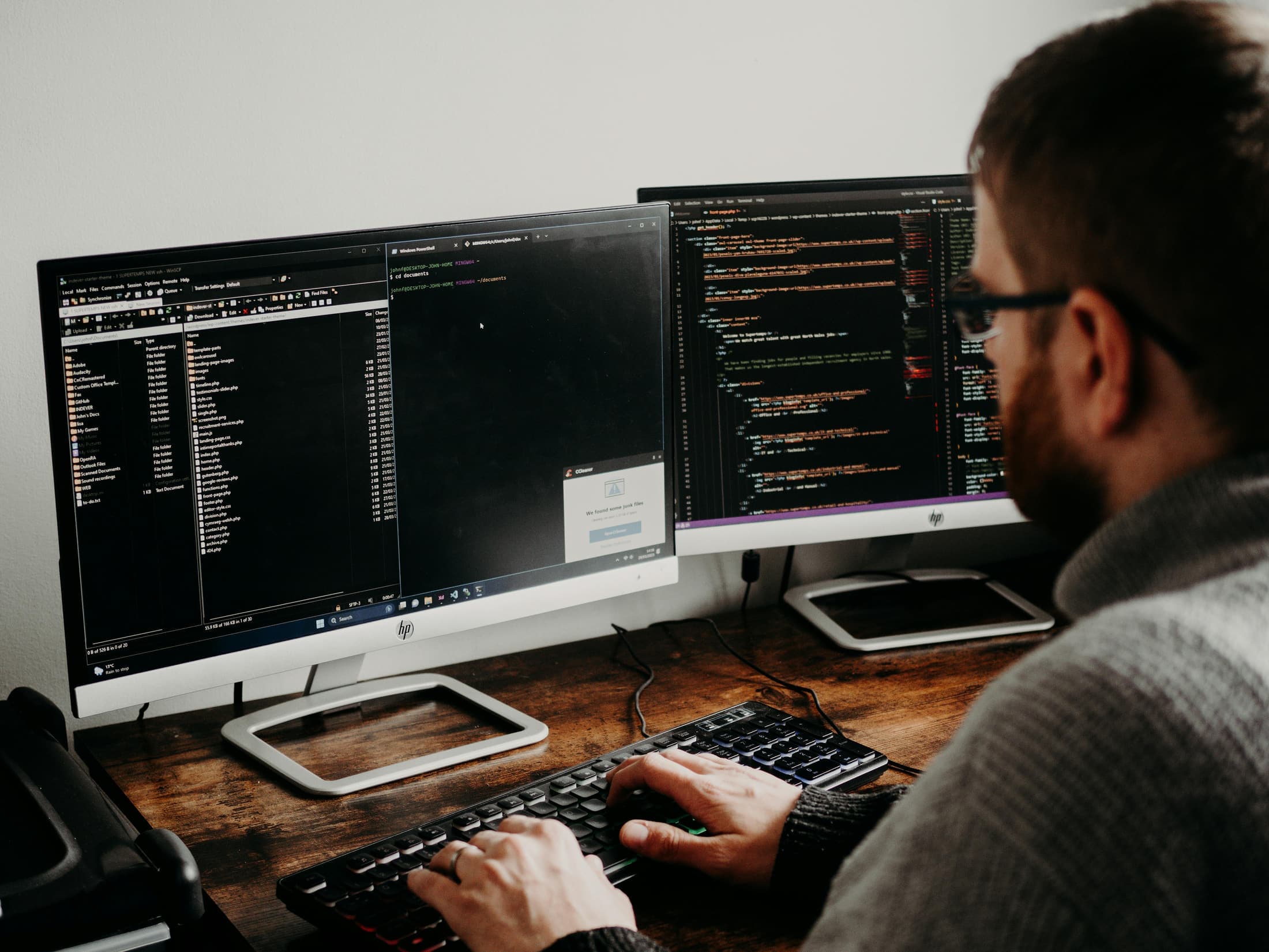 Photorealistic workplace scene showing active work on databases across multiple screens